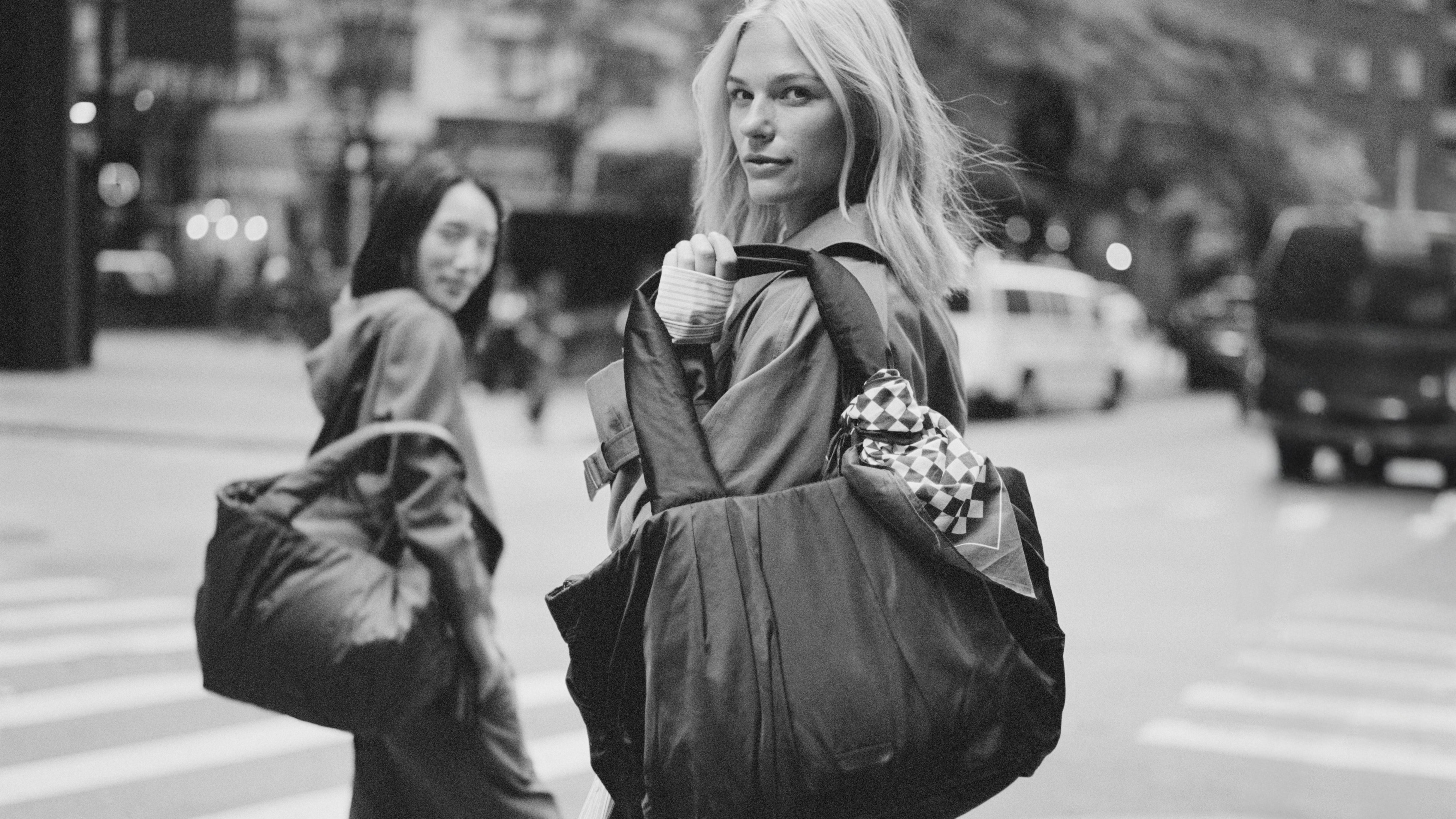 Two woman crossing a street holding TYVY totebags.