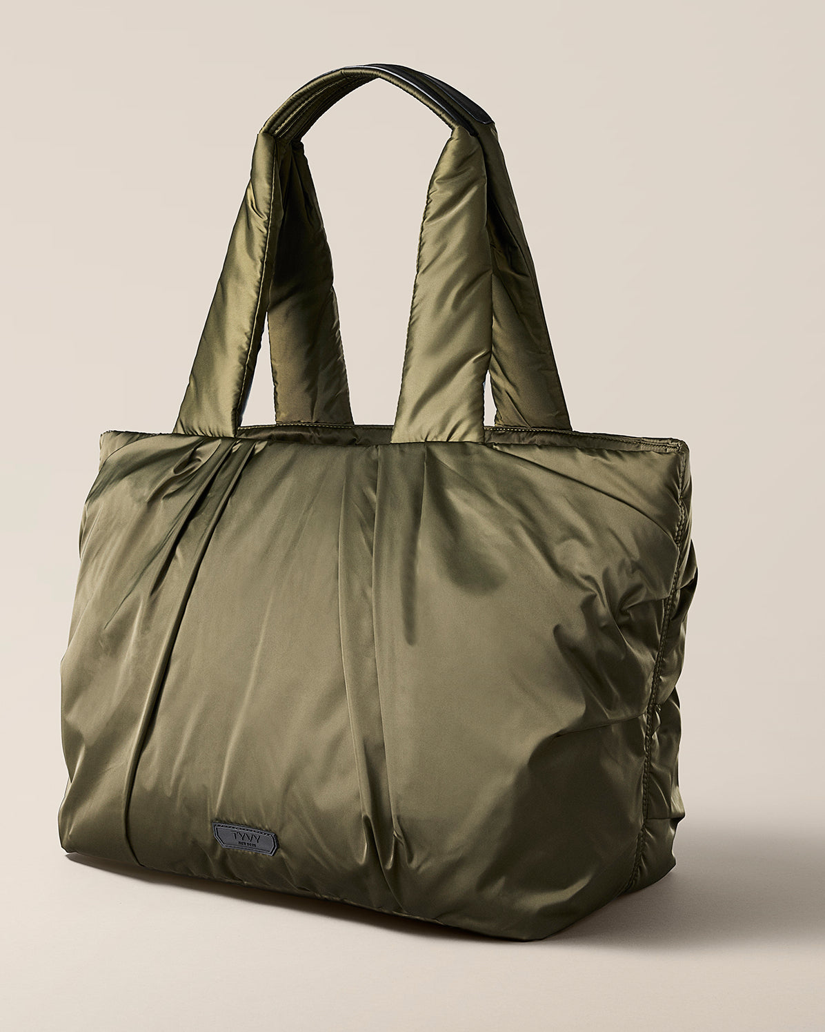 TYVY Aviator Tote bag optimized for travel. Green tote bag on a beige background