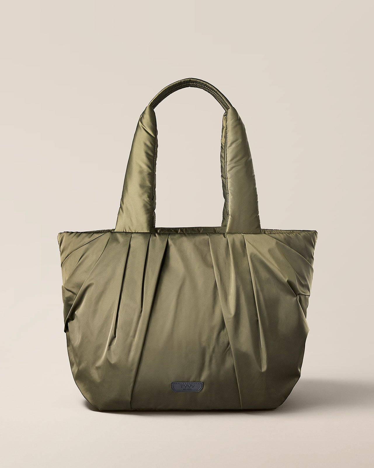 Green tote bag on a beige background. TYVY Aviator Tote bag optimized for travel.