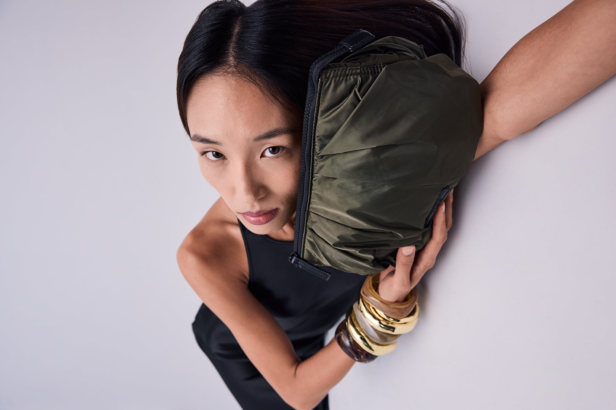 Woman holding an olive green TYVTY tote travel bag against a white background