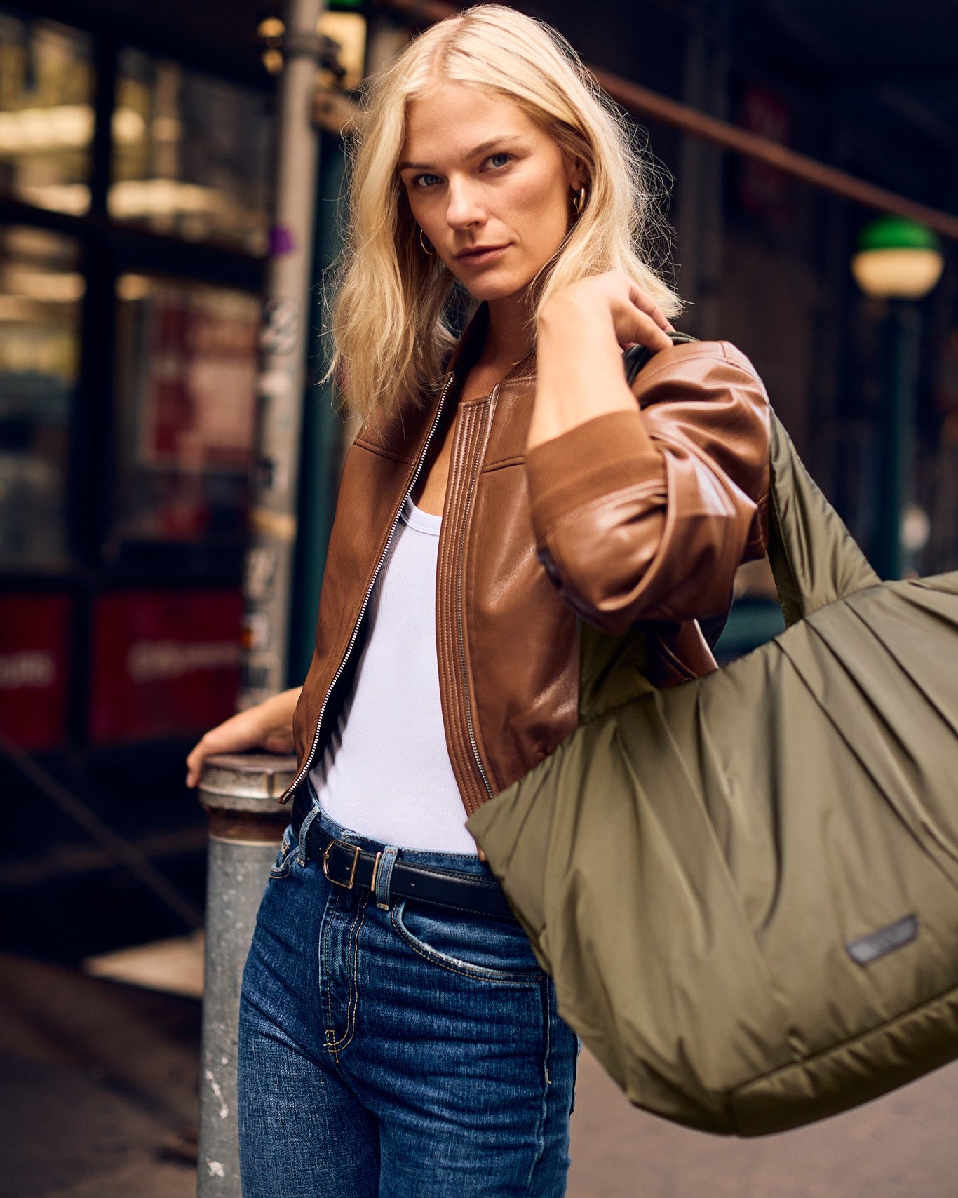 Woman holding an olive green TYVY tote bag on the streets
